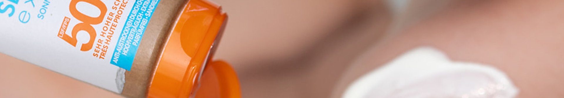 Auf die Schulter eines Kindes wird Sonnenschutz aufgetragen