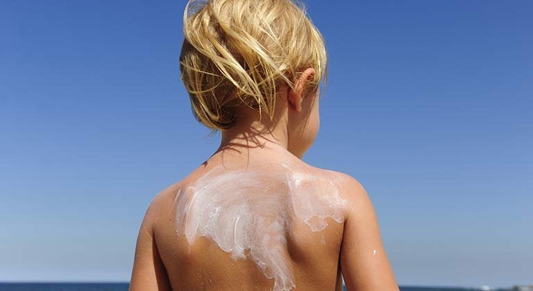 Kind mit Sonnencreme auf dem Rücken