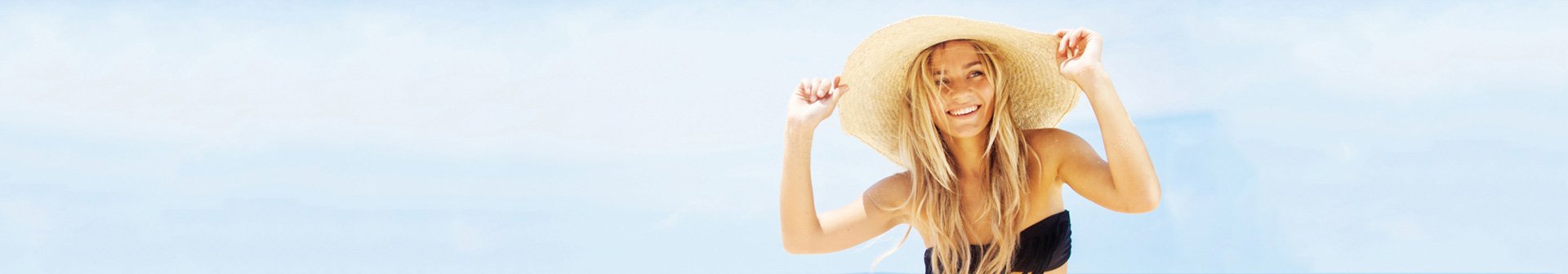 Frau im Bikini und Sonnenhut feiert am Strand