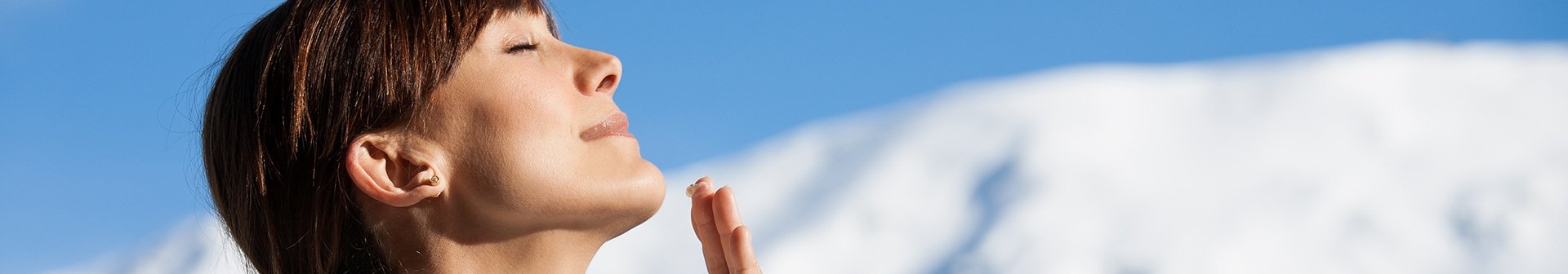 Frau genießt Sonne im Winter mit Schneelandschaft im Hintergrund