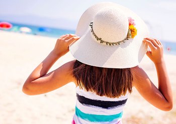 Frau mit Sonnenhut am Strand
