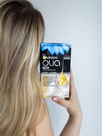 Kopf & Schulterbereich einer Frau mit langen blonden Haaren die das Produkt in ihren Händen hält