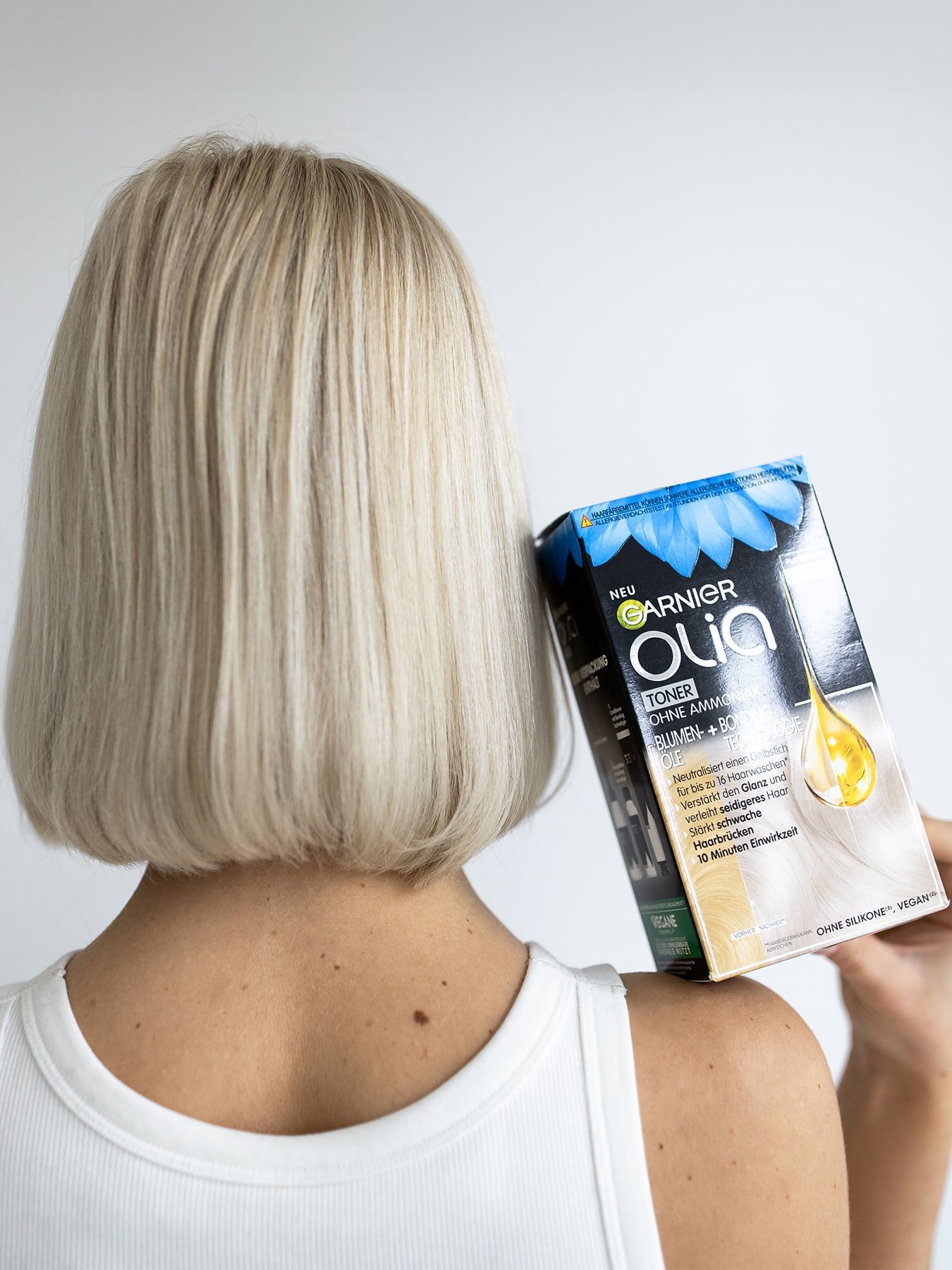 Kopf & Schulterbereich einer Frau mit langen blonden Haaren die das Produkt in ihren Händen hält