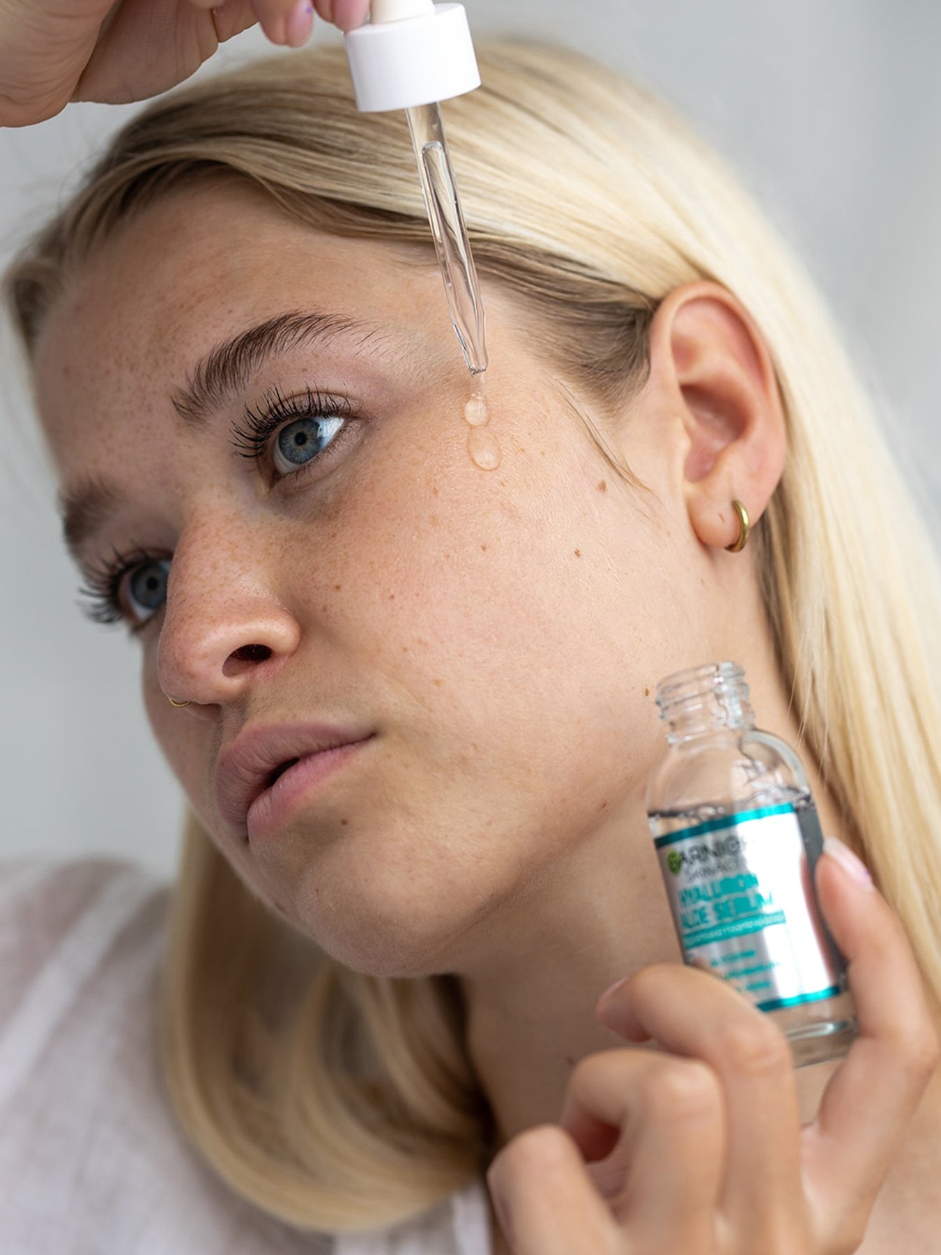 Frau trägt Hyaluron Aloe Serum mit einer Pipette auf ihre Wange auf