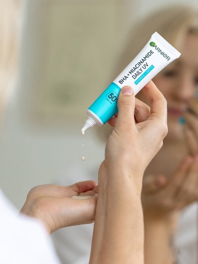 BHA + Niacinamid Daily-UV Anti-Unreinheiten Fluid Invisible wird aus der Tube in eine Handfläche gedrückt