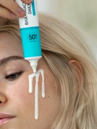 BHA + Niacinamid Daily-UV Anti-Unreinheiten Fluid Invisible wird auf die Wange einer jungen Frau aufgetragen