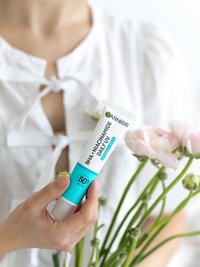 Eine Frau hält eine Tube mit BHA + Niacinamid Daily-UV Anti-Unreinheiten Fluid Invisible in der Hand