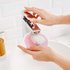 Eine Hand hält ein wiederverwendbares, rosa Pad unter einen Wasserhahn im Waschbecken, um es zu reinigen.