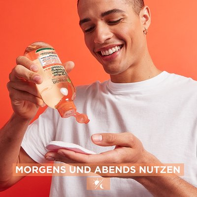 Lächelnder Mann trägt Mizellenwasser auf ein Reinigungstuch auf