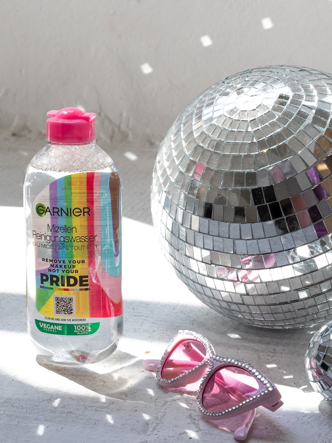 Mizellenwasser Pride Edition steht neben bunter Sonnenbrille und einer Disco-Kugel