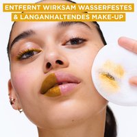 Frau mit zur Hälfte geschminkten und ungeschminkten Gesicht hält ein Reinungspad hoch