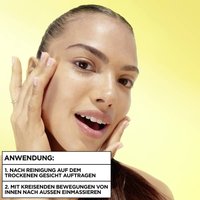 eine junge Frau, die ihr Gesicht in ihren Händen hält und vor einem lebendigen gelben Hintergrund steht.