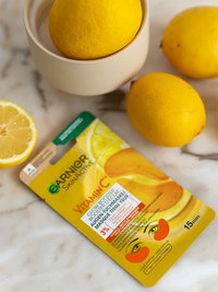 SkinActive Glow Booster Augen-Tuchmaske - Produkt liegend mit einigen Zitronen