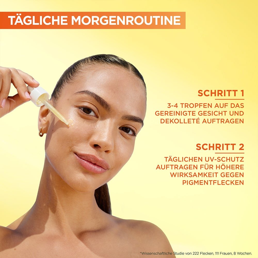 Lächelnde Frau trägt sich Serum aus der Pipette auf die Wange auf