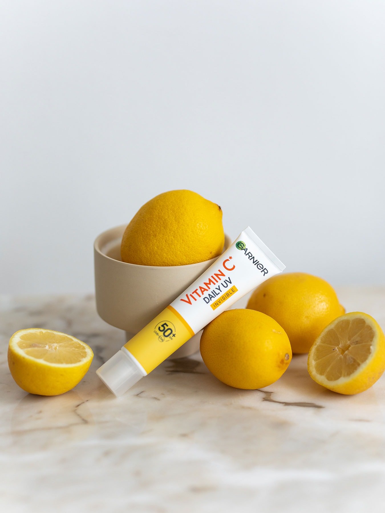 Stillleben mit halbierten Zitronen und dem SkinActive Vitamin C Tägliches Sonnenfluid Invisible mit LSF 50+