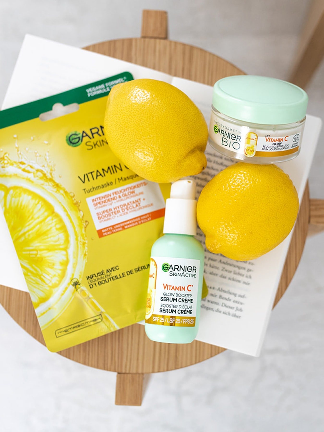 Verschiedene Garnier Vitamin C Feuchtigkeitspflegeprodukte liegen mit Zitronen auf einem kleinen Hocker