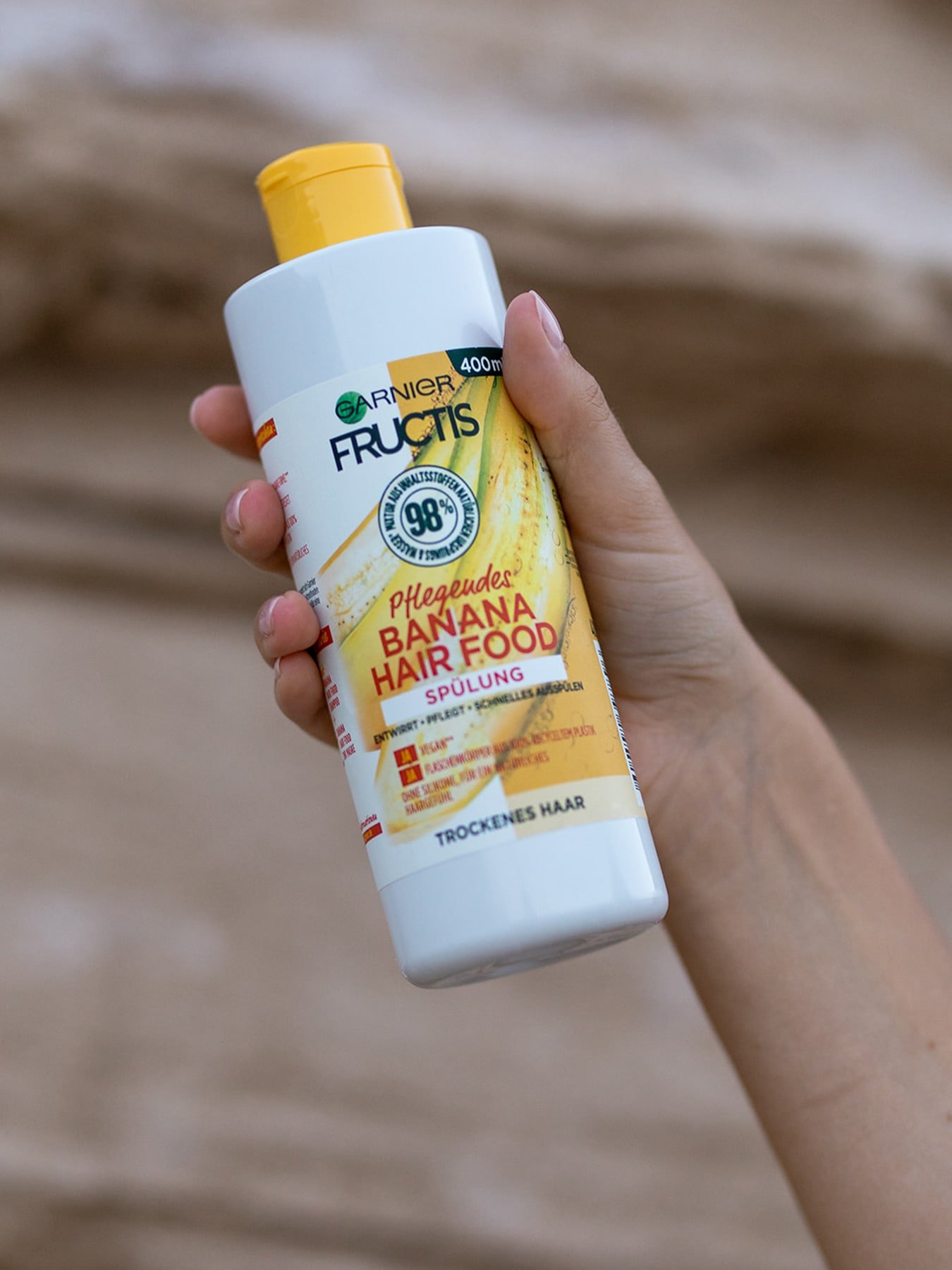Eine Person hält Garnier Fructis pflegende Spülung mit Banane in ihren Händen