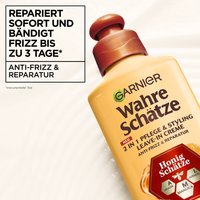 Die Wahre Schätze Leave-In-Creme Honig Schätzeim Vordergrund vor cremiger, sanfter Textur, oben links ein Schriftzug mit Produktbeschreibung
