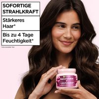 Sofortige Strahlkraft: Brünette Frau hält die Wahre Schätze Traube Hydraboost 1-Minute Haarkur vor sich