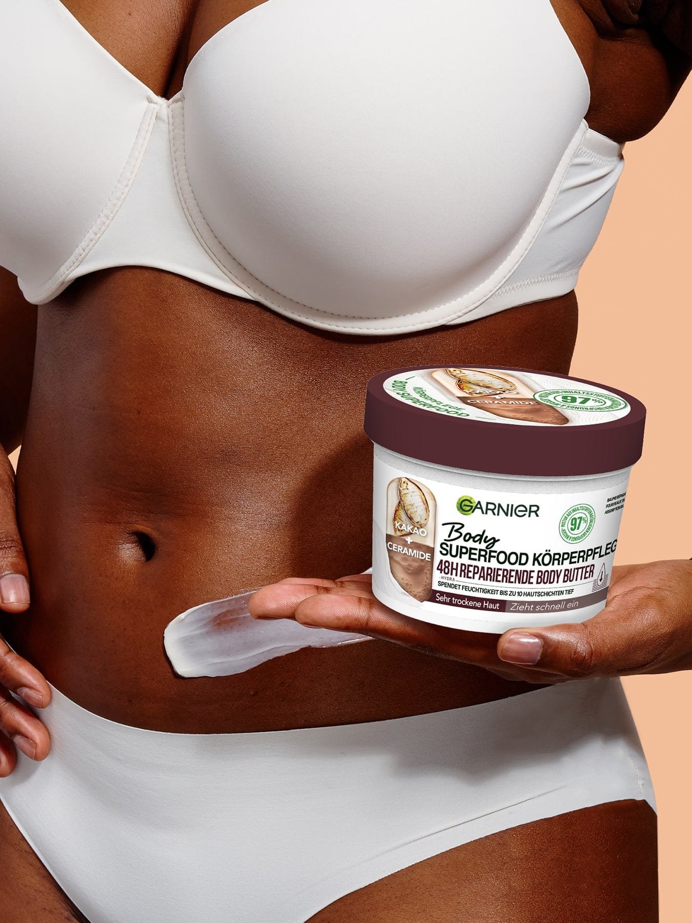 Eine Frau hält eine Packung Body Superfood 48h reparierende Body Butter auf ihrer Handfläche