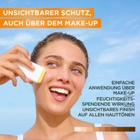 Model die glücklich lächelnd vor einem blauen Himmel steht und den Garnier Sunstick auf ihrer Backe anwendet.
