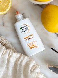 Super UV Sonnenschutzfluid mit Vitamin C LSF 50+ Produkt liegend mit einigen Zitronen