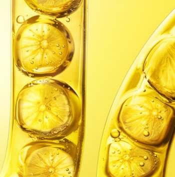 Visualisierung von Vitamin C als Antioxidans, Zitronenscheiben in gläsernem Behältnis vor gelbem Hintergrund