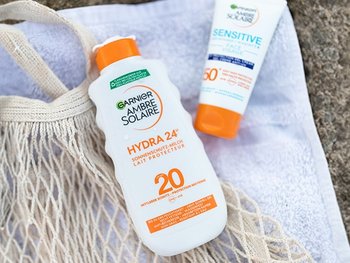 Ambre Solaire Sonnenschutzprodukte lieben im Sand auf einem Handtuch