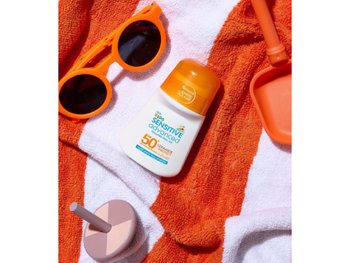 Ambre Solaire Sonnenschutzprodukte lieben im Sand auf einem Handtuch