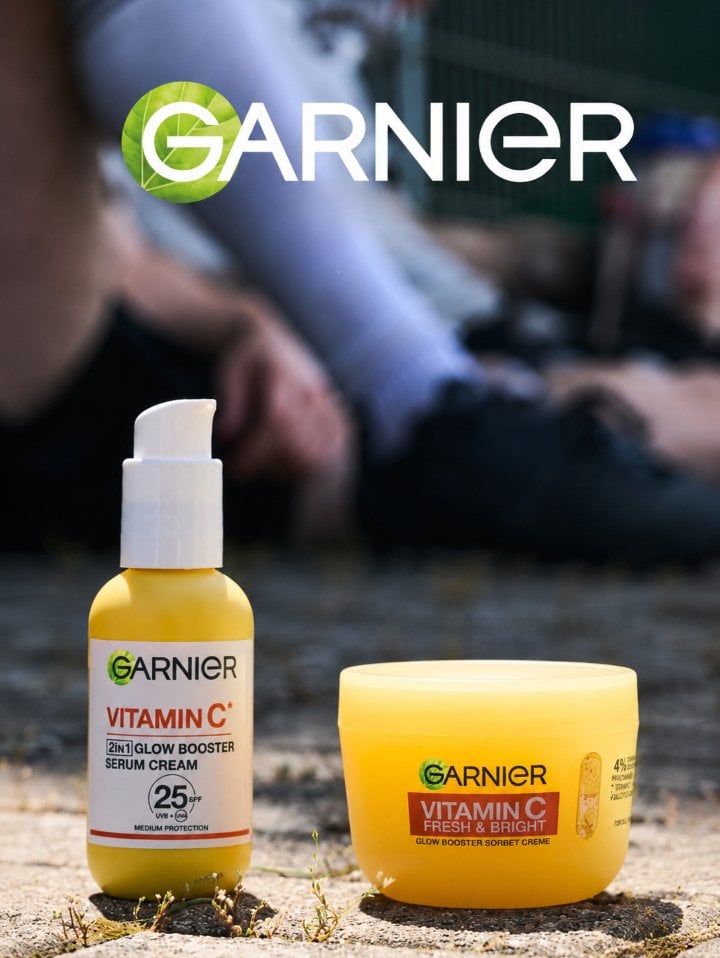 5 Garnier Haar und Hautpflege Produkte stehen in der Sonne auf einem sonnigen Sportplatz. Spieler sitzen in der Ferne verschwommen im Hintergrund.