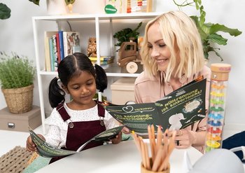 Janin Ullmann betrachtet zusammen mit einem Mädchen ein Malbuch