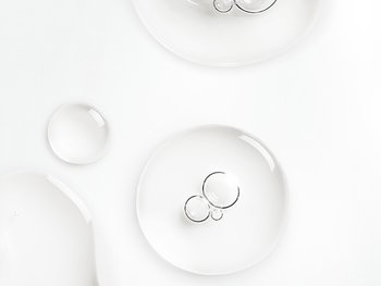 Detailaufnahme einer transparente Flüssigkeit mit Bläschen vor hellgrauem Hintergrund