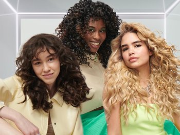 Gruppe von drei Frauen mit Locken in verschiedenen Farben und Formen