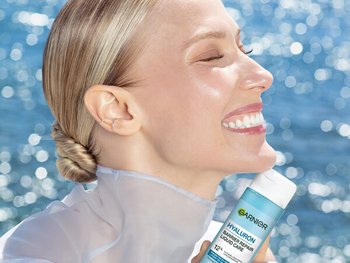 Lächelnde Frau in der Sonne; im Hintergrund Wasser