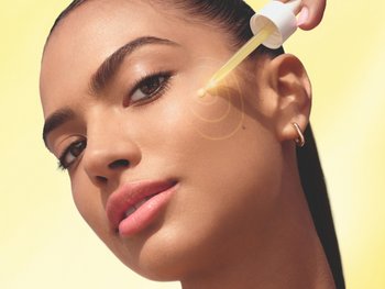 Frau trägt Serum aus dem Applikator auf ihre linke Wange auf