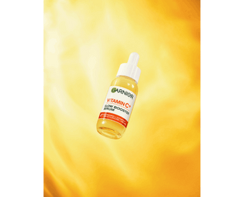 Das Garnier Vitamin C Glow Booster Serum vor einem immersiven gelben Hintergrund.