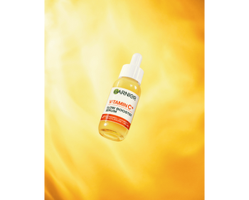 Das Garnier Vitamin C Glow Booster Serum vor einem immersiven gelben Hintergrund.