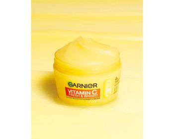 Das Garnier Vitamin C Glow Booster Serum vor einem immersiven gelben Hintergrund.