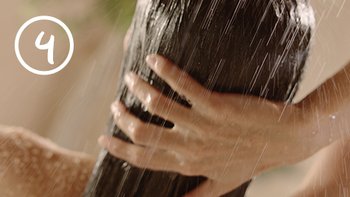 Frau wäscht ihre Haare mit Wasser