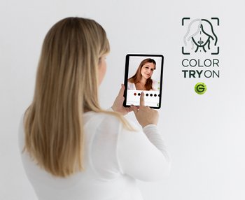 Eine junge Frau wählt den Selfie-Modus auf ihrem Tablet, um die Garnier Haarfarben mit dem Virtual Try On Tool zu testen